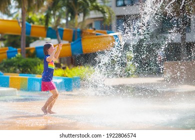 Child Playing Under Tip Bucket In Water Park. Kids Play With Splash Dump Bucket. Family Fun In Amusement Center On Hot Summer Day. Sun Protection For Children. Water Slides For Kid.