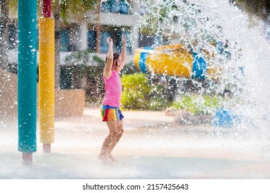 Child Playing Under Tip Bucket In Water Park. Kids Play With Splash Dump Bucket. Family Fun In Amusement Center On Hot Summer Day. Sun Protection For Children. Water Slides For Kid.