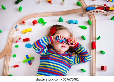 Child Playing With Wooden Train, Rails And Cars. Toy Railroad For Kids. Educational Toys For Preschool And Kindergarten Children. Little Girl At Daycare. View From Above, Kid Playing On The Floor.