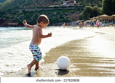 Child plays with a ball on the beach.