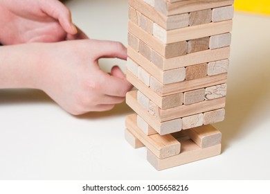 The Child Plays In Board Game Falling Tower Of Wooden Blocks