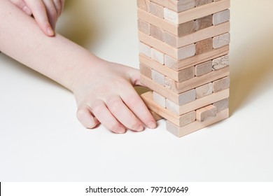 The Child Plays A Board Game Of A Falling Tower Of Wooden Blocks