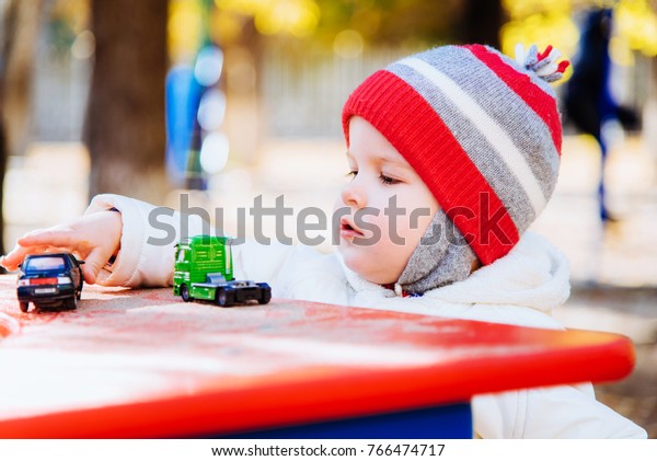 the child plays cars on\
the street