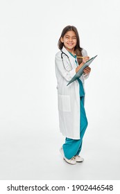 Child Plays Doctor, Future Profession. Cute Hispanic Female Kid Writes Medical Treatment On Her Clipboard. White Background