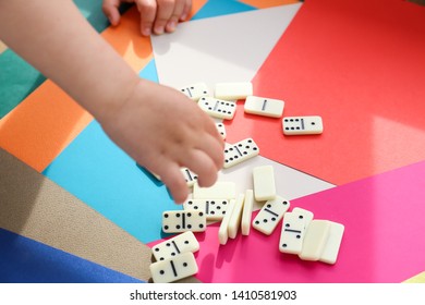 The Child Plays Dominoes On Colored Paper.