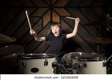 The child plays the drums. Boy musician behind a drum kit.