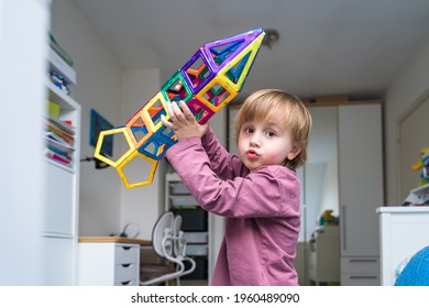 Child Plays With A Magnetic Constructor On A Carpet In A Room. Boy Building A Rocket From Blocks. Kid Playing With Colorful Toys.