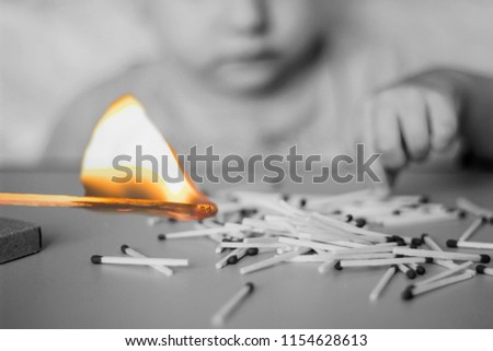 A child plays with matches in the foreground a burning match, a child and matches, a fire, dangerous, black and white