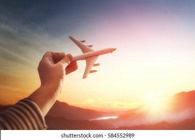 Child plays with a toy airplane in the sunset and dreams of journey. Hand with small plane close up.