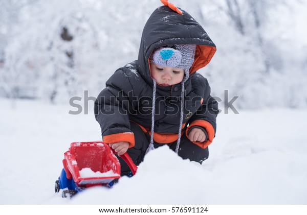 \
A child\
plays a toy truck in the snow. Shovel, snow, truck.Children\'s toy\
cars. Car Models. Kids toys. The child is played by an car. Little\
boy playing with snow, spade and\
truck.