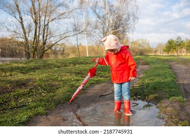 Child plays with umbrella after the rain in red rubber boots and a raincoat. - Powered by Shutterstock