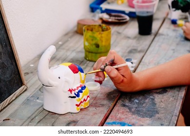Child plays to unleash his creativity by decorating a white plaster figure with colored paints, during the summer holidays. - Shutterstock ID 2220494693