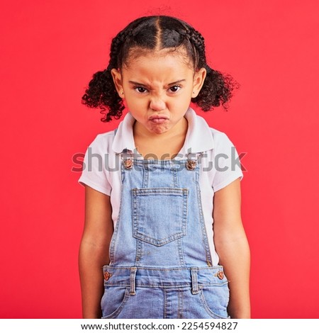 Child, portrait or angry face on isolated red background in emoji tantrum, behavior or stubborn studio problem. Mad, annoyed or frustrated little girl and sulking, grumpy or anger facial expression