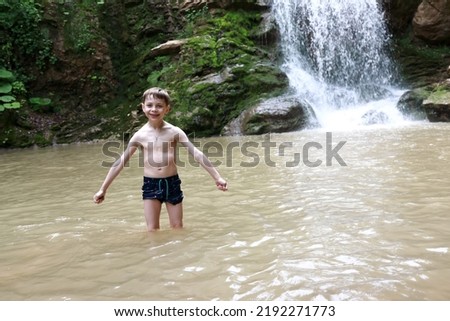 Child posing in Rufabgo stream next to waterfall Shum, Adygea