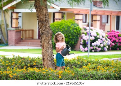 Child Pouring Water On The Trees. Cute Little Boy Watering Flowers With Watering Can