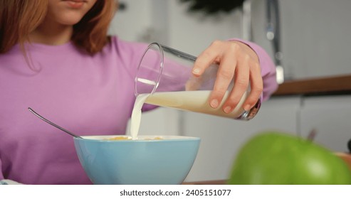 Child pours milk into cereal for healthy breakfast close-up cinematic slow-motion of healthy breakfast milk swirling in bowl. Kid enjoys healthy breakfast with milk and cereal at table. - Powered by Shutterstock