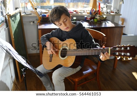 Child is practicing acoustic guitar in his room