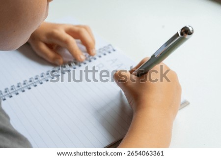 Child practicing handwriting in notebook - close-up educational series