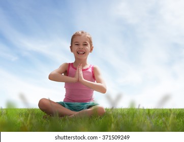 child practicing yoga on the grass outdoors - Powered by Shutterstock