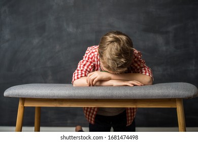 Child Pray. Little Boy Stay On Knees With Head On Hands On Bench