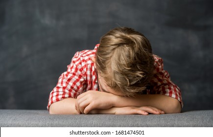 Child Pray. Little Boy Stay On Knees With Head On Hands On Sofa