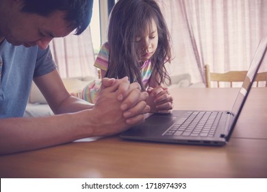 Child praying with father parent with laptop, family and kids worship online together at home, streaming online church service, social distancing, new normal concept