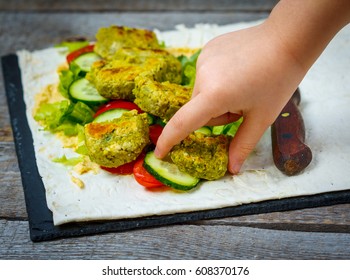 The Child Is Preparing Falafel With Hummus On Pita Bread And Vegetables. Love For A Healthy Vegan Food Concept