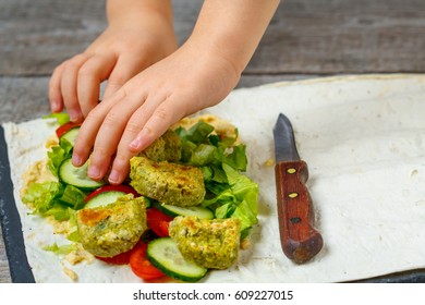 The Child Is Preparing Falafel With Hummus On Pita Bread And Vegetables. Love For A Healthy Vegan Food Concept