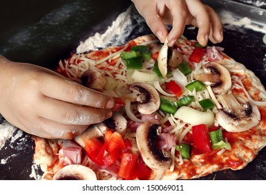 Child preparing pizza with the hands of a kid and fresh ingredients as mushrooms mozzarella cheese onions and dough as delicious food for dinner or learning how to cook at a culinary class. - Powered by Shutterstock