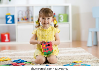 Child preschooler girl plays logical toy learning shapes and colors at home, daycare or nursery