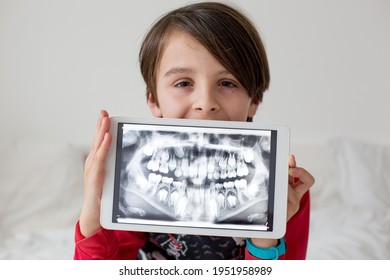 Niño, niño preadolescente, sosteniendo una tableta con una foto de sus dientes de rayos X del dentista