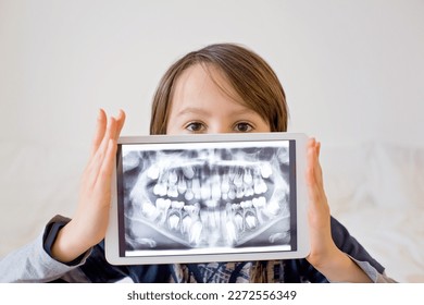 Niño, niño preadolescente, sosteniendo una tableta con una foto de sus dientes de rayos X del dentista