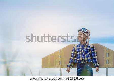 Child pretend to be pilot. Kid having fun at outdoor.He used paper to make wings. Summer vacation and travel concept.