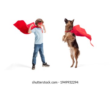 Child pretending to be a superhero with his super dog in red coats isolated on white studio background. Dreams, emotions, pet's love and friendship, motivation concept. Powerful together. Copyspace.