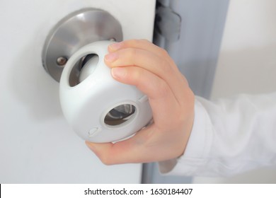 Child Proof Door Knob Covers Over Doorknob With A Kid's Hand Trying To Open The Door