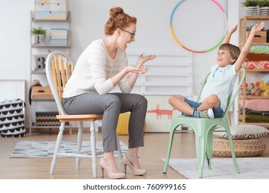 Child Psychologist And Young Kid With ADHD During Therapy Session In Primary School Interior