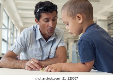 Child Pupil With Parent Or Teacher Reading A Book In Classroom Public Library. 