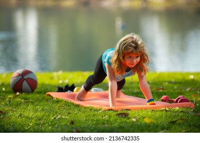 Child is pushing up on the green meadow, working out wearing sportswear, t-shirt outdoor. Kids doing push up outdoor. Gymnastic for children. Kid pushing up.