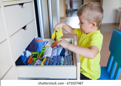 The Child Puts His Clothes On. The Boy Pulls The T-shirt Out Of The Closet.