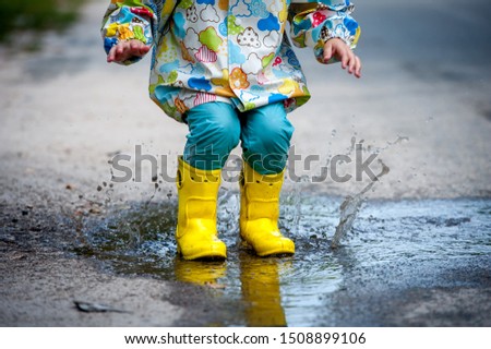 Similar – Image, Stock Photo Small infant boy wearing yellow rubber boots and yellow waterproof raincoat standing in puddle on a overcast rainy day. Child in the rain.