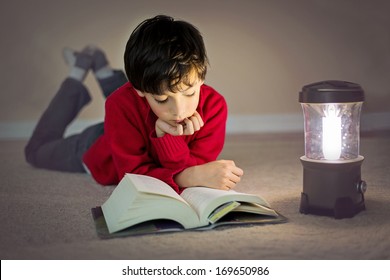 a child reading a book by the light of a lantern - Powered by Shutterstock