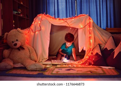 the child is reading a book with a flashlight