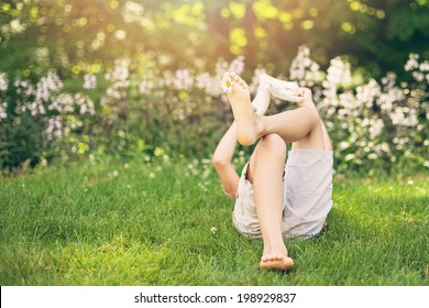 Child Reading A Book In A Garden