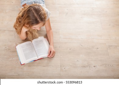 Child Reading Book At Home. Girl Lying And Read Indoors