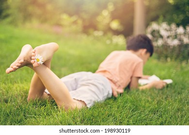 Child Reading A Book In A Park