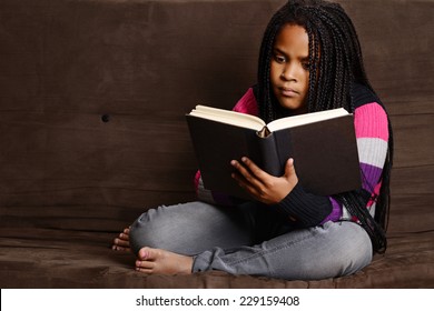 Child Reading Book Sitting On Couch