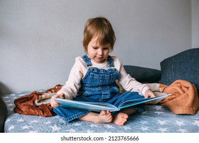 Child Reads His Favorite Book At Home. Kid Looks At Pictures In Fairy Tales.