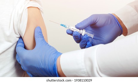 Child receiving coronavirus vaccination in clinic. Doctor giving shot or vaccine to a patient's shoulder. Vaccination and prevention against flu or virus. Coronavirus pandemic. Covid-19 vaccine .
