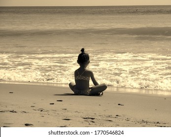 child relaxes at sea. look at the waves of the sea. poza lotus yoga. sepia style picture.