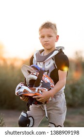 Child Rider On Motorcycle. Small Biker Dressed In A Protective Suit And Helmet. The Kid Is Engaged In Motocross